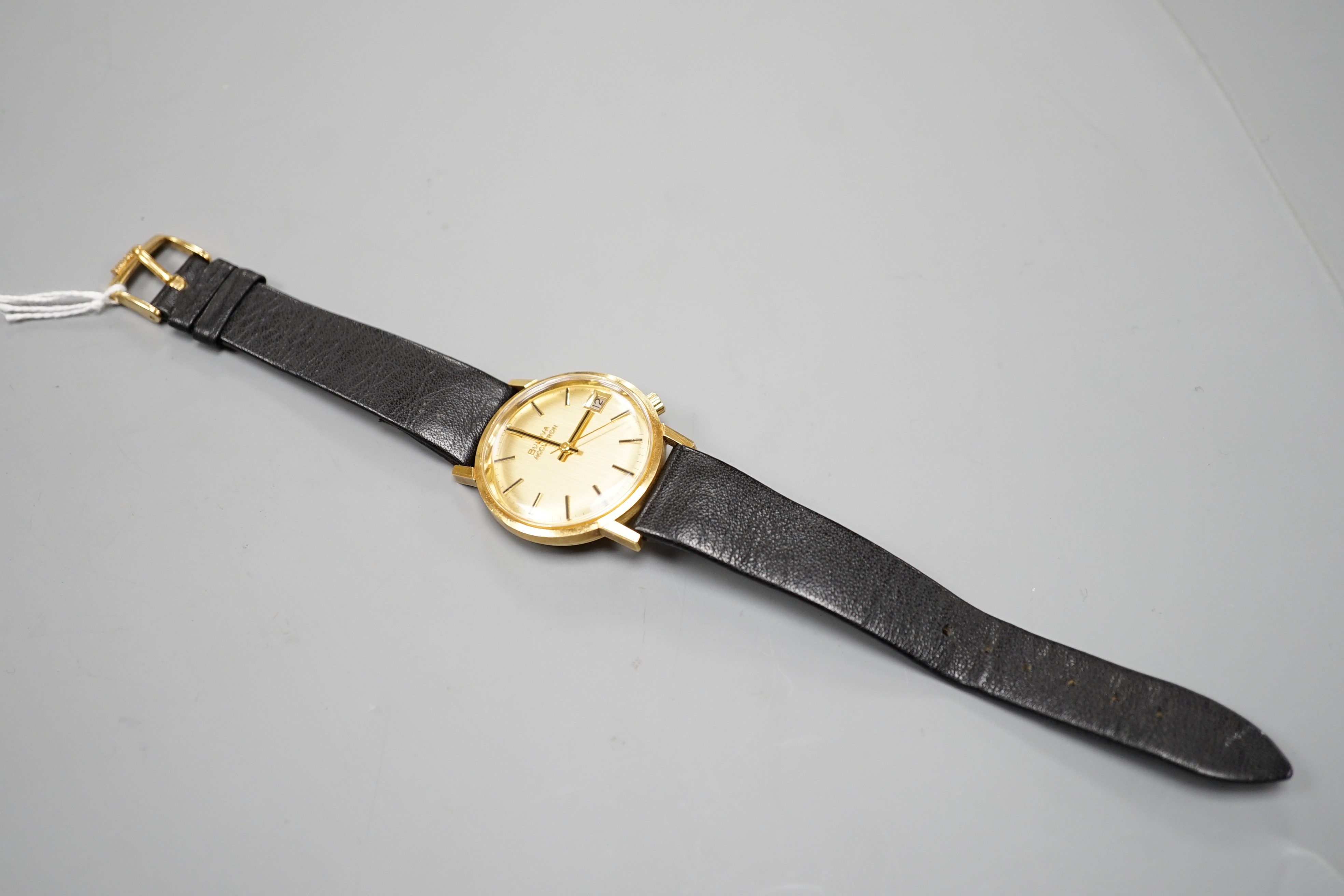 A gentleman's 750 yellow metal Bulova Accutron wrist watch, on a black leather strap, case diameter 34mm, gross weight 42.2 grams.